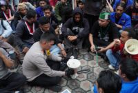 Caption:
Kapolres Cirebon Kota, AKBP Eko Iskandar duduk bersama pengunjuk rasa di halaman Kantor DPRD Kota Cirebon, Jum'at (21/02-2025). (Ft. Ch)